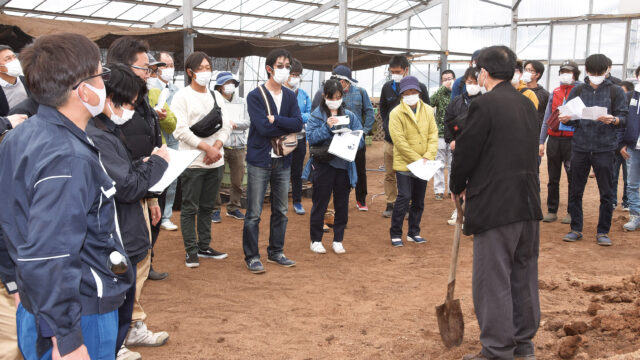 伊藤さんを囲んで話を聞く参加者。ハウスの中は真夏のように暑い