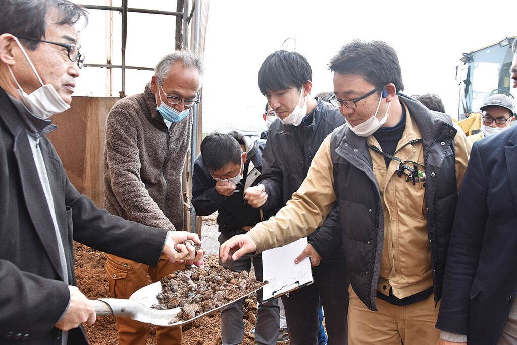 堆肥化したオガ屑に手で触れる参加者